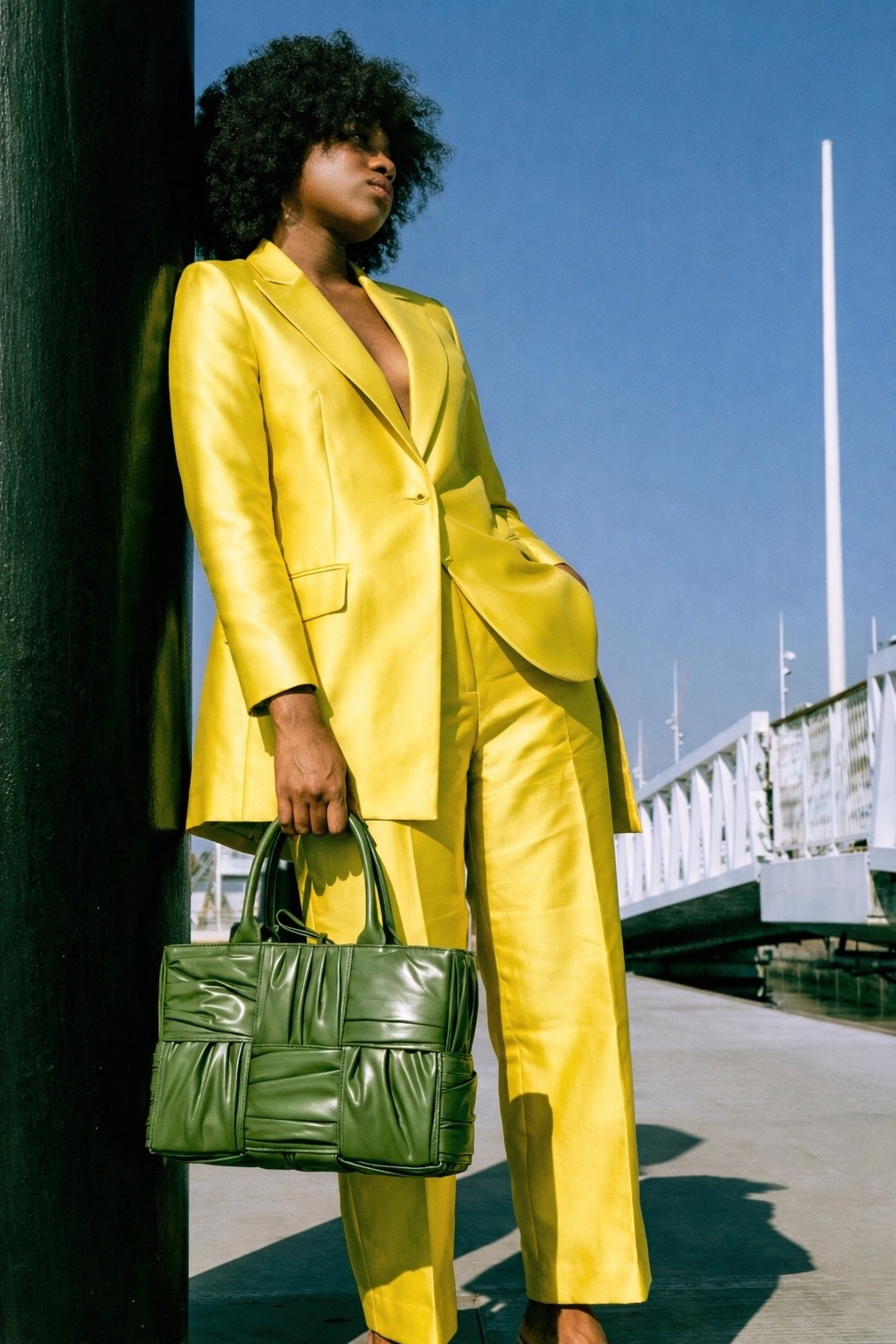 Woman in a yellow suit carrying a green designer handbag